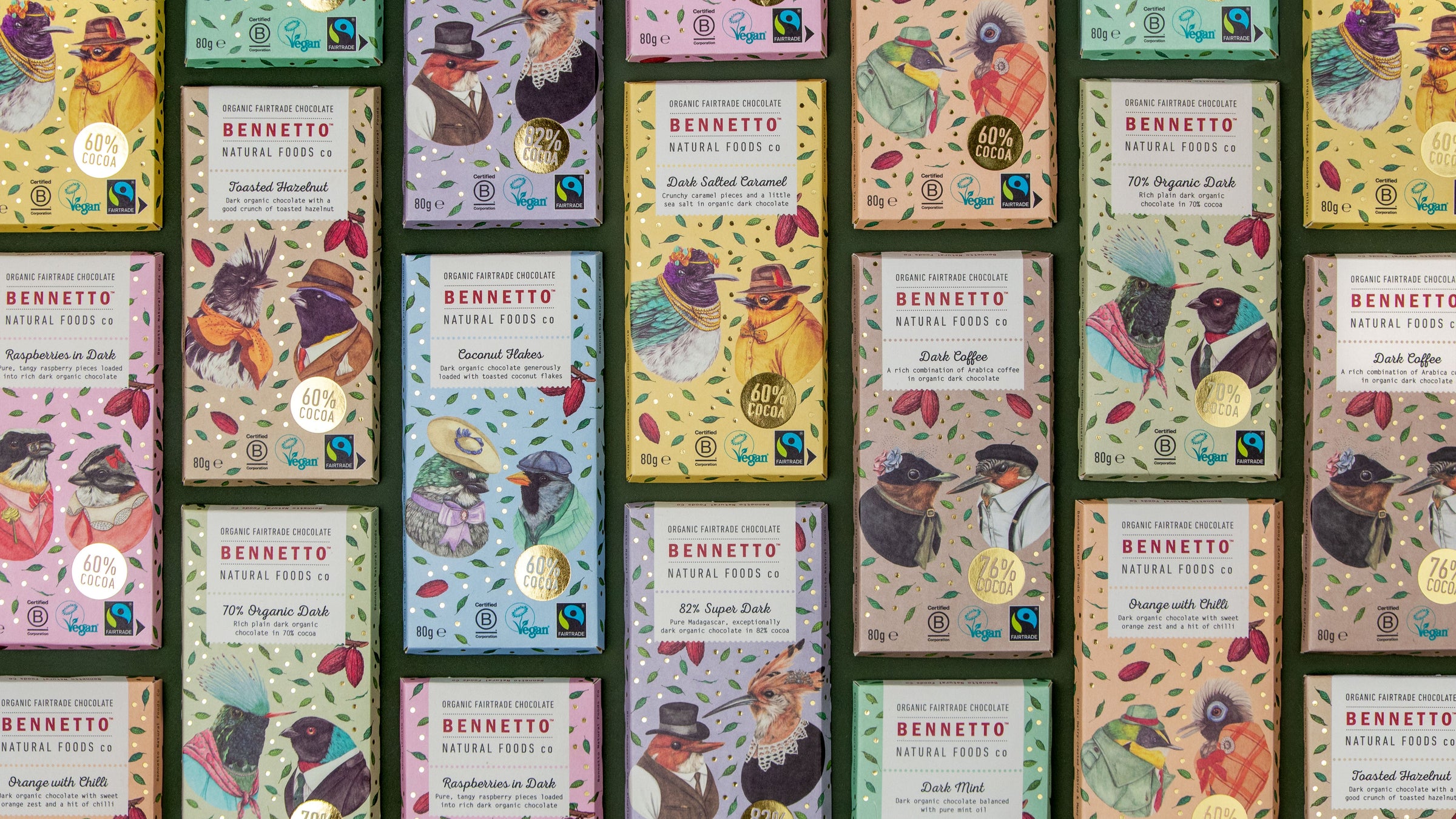 Flatlay collection of colourful Bennetto chocolate packaging with birds and brand logos on a green background