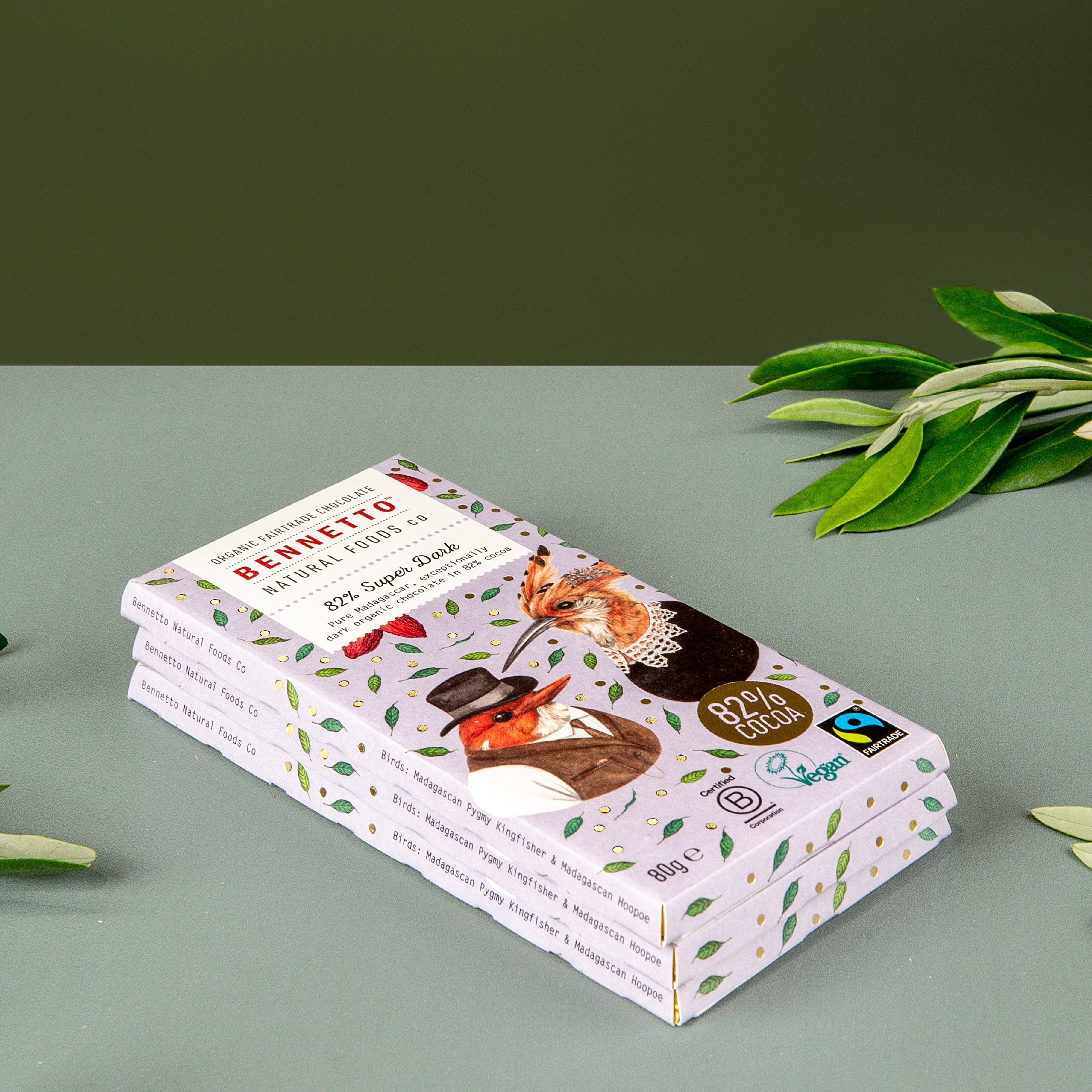 A stack of 3 bars of Bennetto 82% Super Dark Fairtrade and organic chocolate sits on a green table